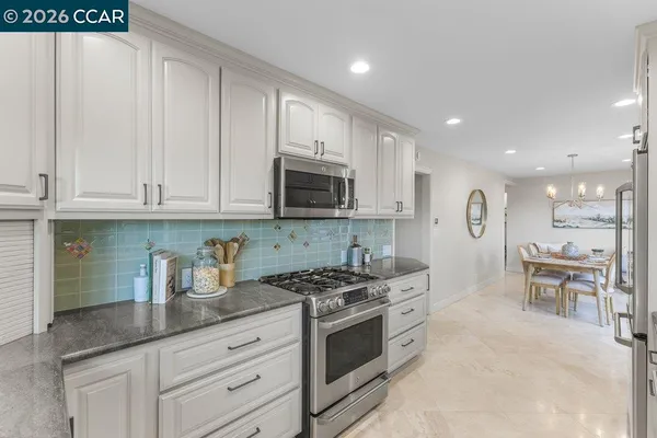 a kitchen with granite countertop white cabinets and stainless steel appliances