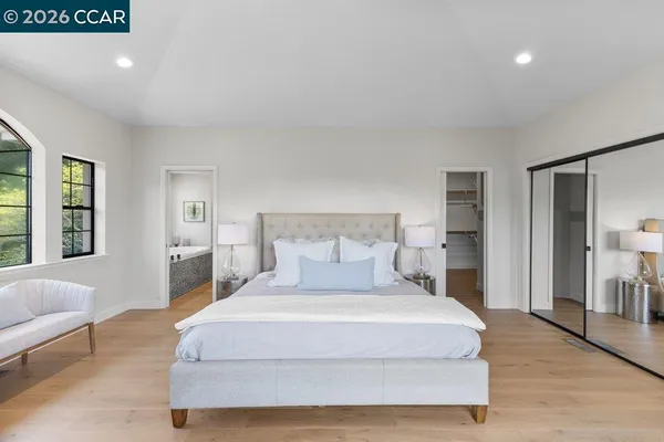 a bedroom with a large window and a wooden floor