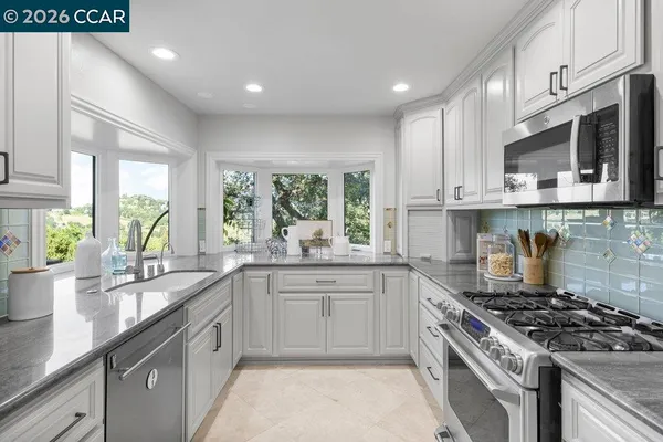 a large kitchen with stainless steel appliances granite countertop a stove and a sink