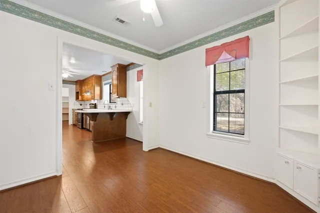 a view of an empty room with window and wooden floor