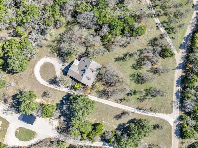 an aerial view of a house with a yard and a large tree