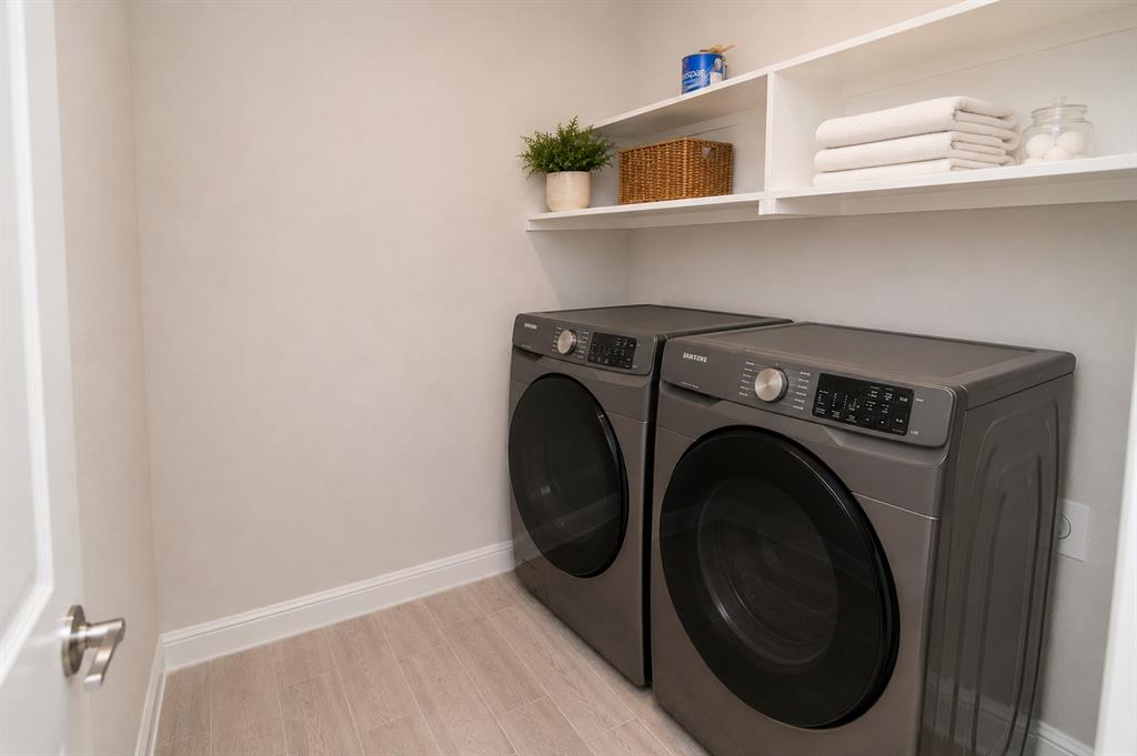 1804 Mensa Drive Haslet, TX 76052 - Photo 16 of 30 Dedicated laundry area featuring a front-load washer and dryer set, wood-finish flooring, and white wall shelving