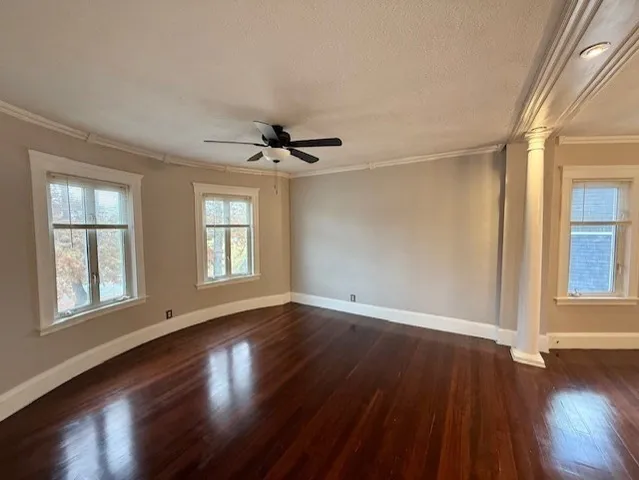a view of an empty room with wooden floor and a window