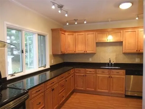 a kitchen with granite countertop white cabinets white appliances a sink and a large window