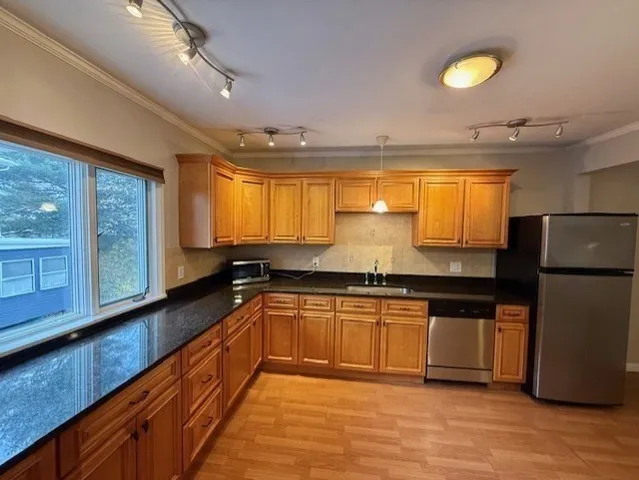 a large kitchen with stainless steel appliances granite countertop a refrigerator a stove a sink and a large window