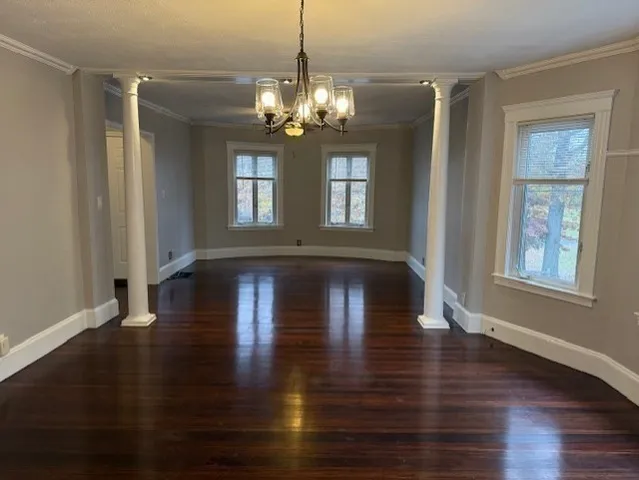 a view of a room with wooden floor chandelier and windows