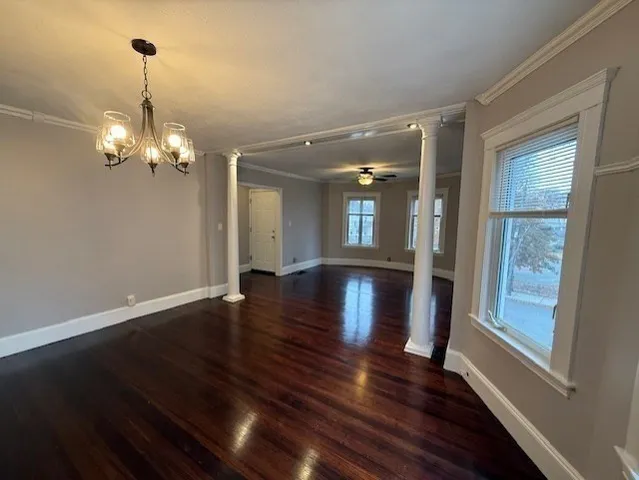 a view of a room with wooden floor chandelier and windows