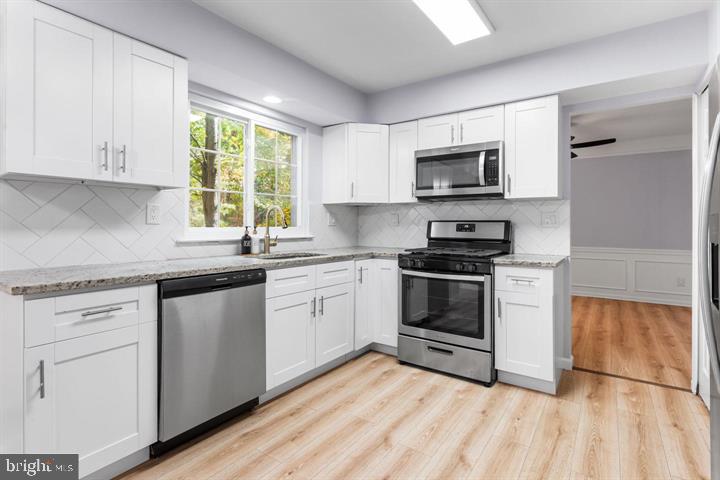 2807 Falling Brook Terrace Hyattsville, MD 20783 - Photo 11 of 48 a kitchen with stainless steel appliances granite countertop white cabinets a sink a stove a microwave and wooden floors