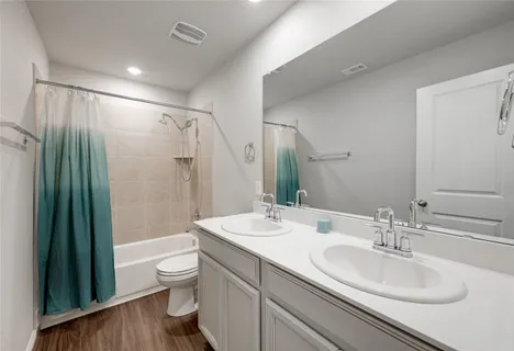 a bathroom with a double vanity sink toilet mirror and shower