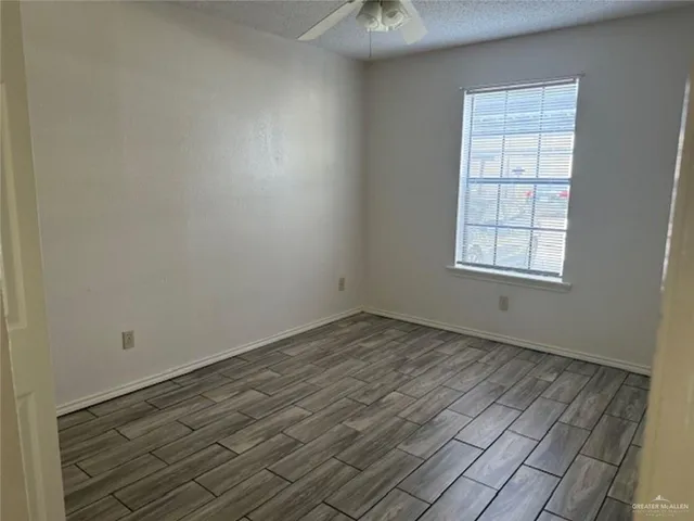 a view of a hallway with wooden floor and a refrigerator