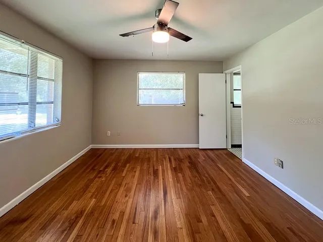 a view of an empty room with wooden floor and a window