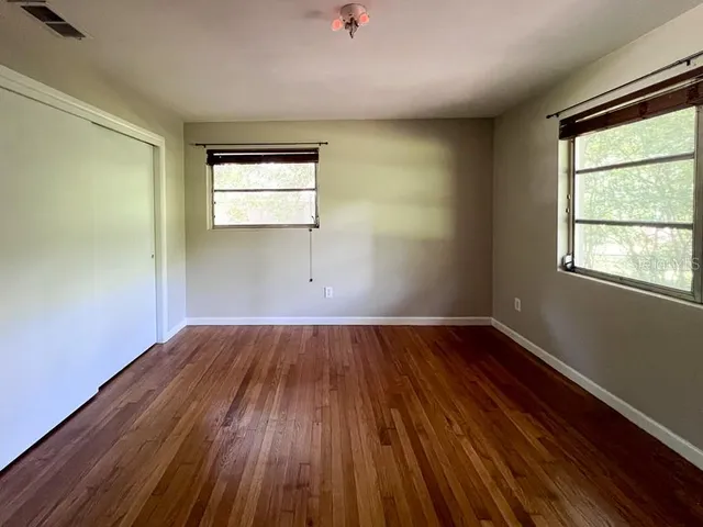 an empty room with wooden floor and windows