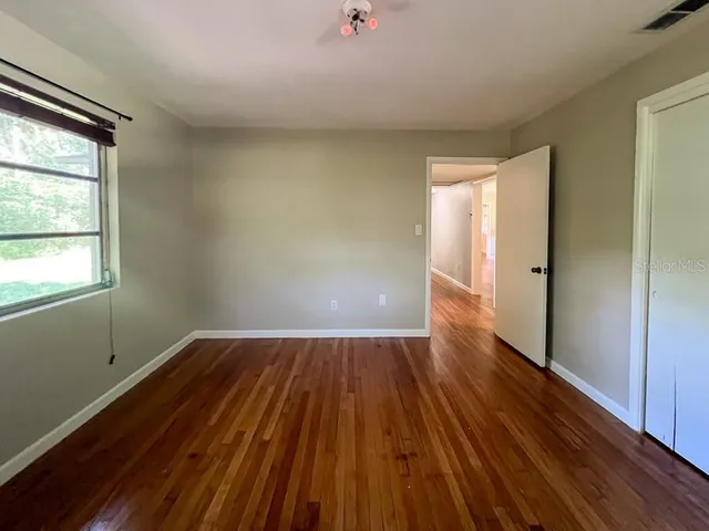 a view of an empty room with wooden floor and a window