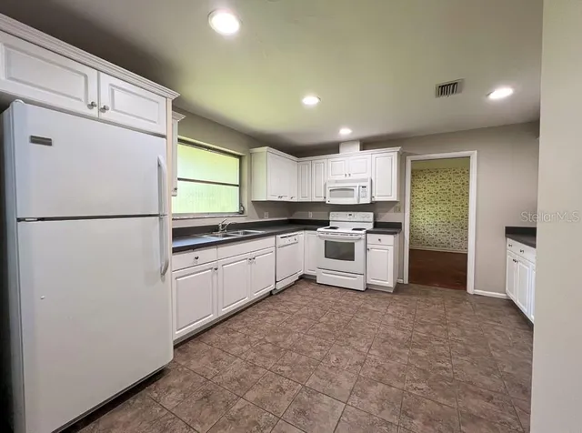 a kitchen with granite countertop a refrigerator and a sink