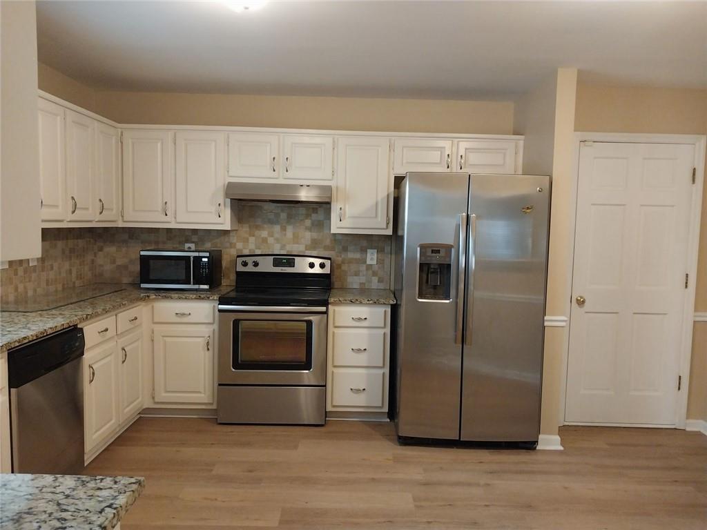4820 Westbourne Drive Powder Springs, GA 30127 - Photo 7 of 16 a kitchen with a refrigerator stove and white cabinets