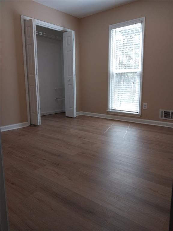 4820 Westbourne Drive Powder Springs, GA 30127 - Photo 8 of 16 an empty room with wooden floor and windows with curtains