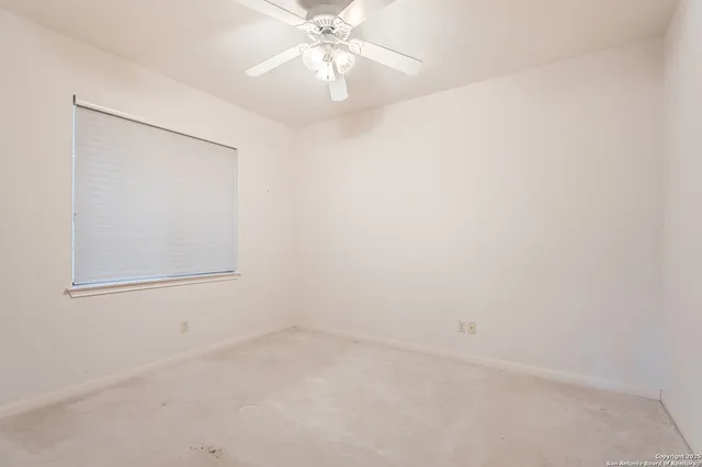 an empty room with a window and a fan