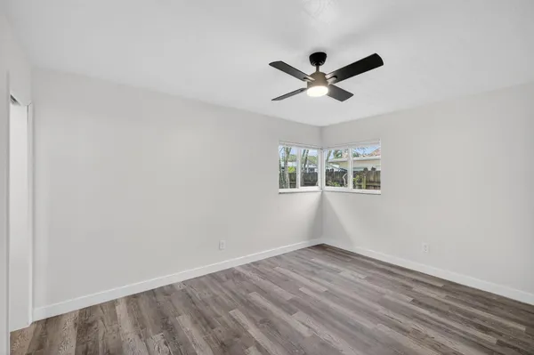 a view of empty room with wooden floor and ceiling fan