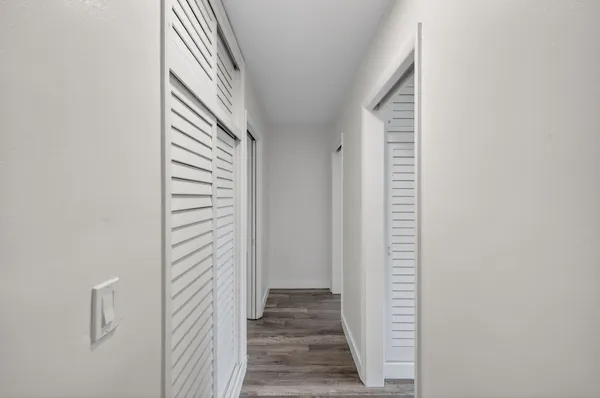 an empty room with wooden floor ceiling fan and windows