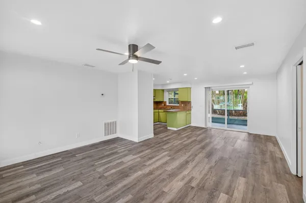 a view of an empty room with a window and wooden floor