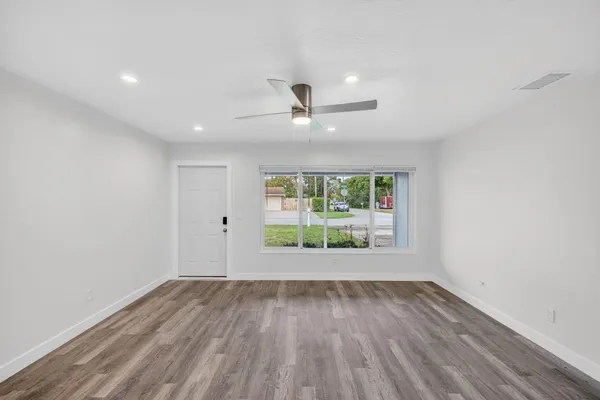 an empty room with wooden floor and windows