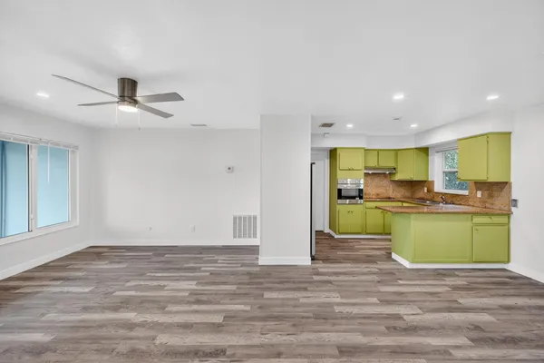 a large kitchen with stainless steel appliances granite countertop a refrigerator a stove and a wooden floors