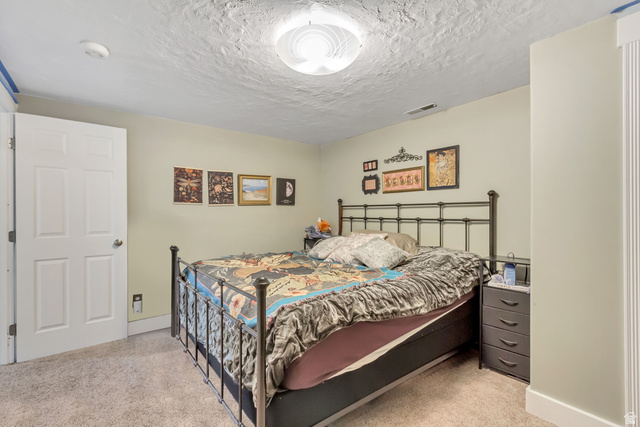 65 West 700 North Bountiful, UT 84010 - Photo 16 of 29 Room featuring neutral wall tones, textured ceiling, a four-panel door, and light-toned carpeting