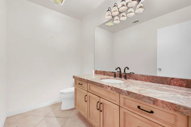 a bathroom with a granite countertop sink vanity mirror and toilet