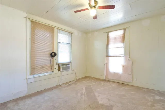 a view of an empty room with a window and dresser