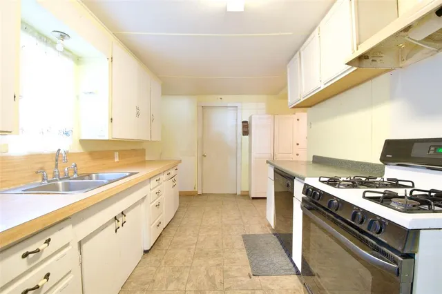 a kitchen with granite countertop a sink stove and cabinets
