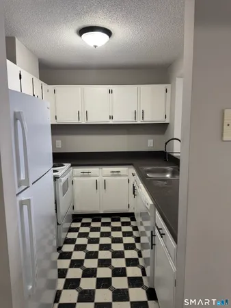 a kitchen with a refrigerator and white cabinets