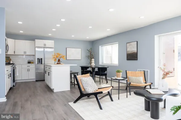 a living room with furniture a rug kitchen view and a window