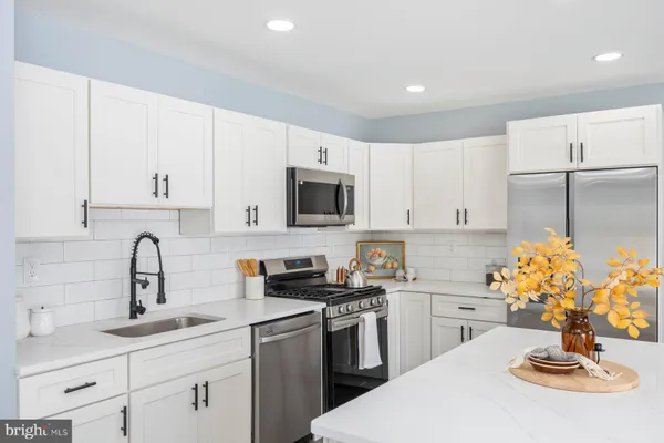 a kitchen with stainless steel appliances a sink a stove a microwave a sink a refrigerator and cabinets