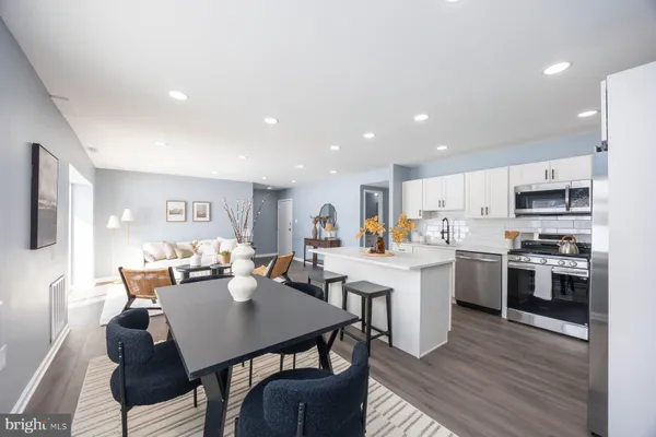 a kitchen with stainless steel appliances kitchen island granite countertop a stove a sink a dining table and chairs