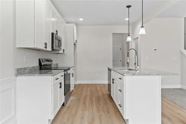 a kitchen with granite countertop a sink a counter space appliances and cabinets