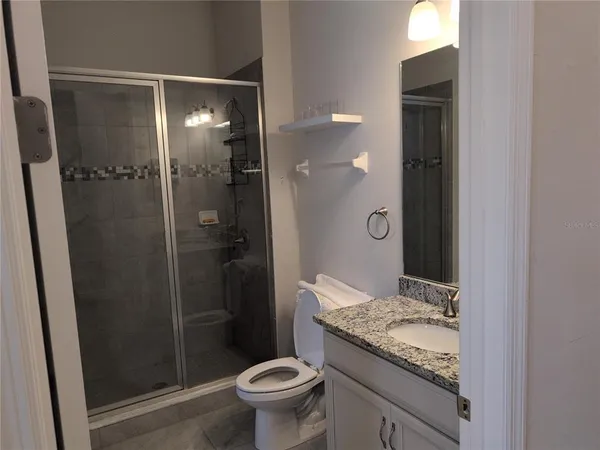 a bathroom with a granite countertop sink a toilet and shower