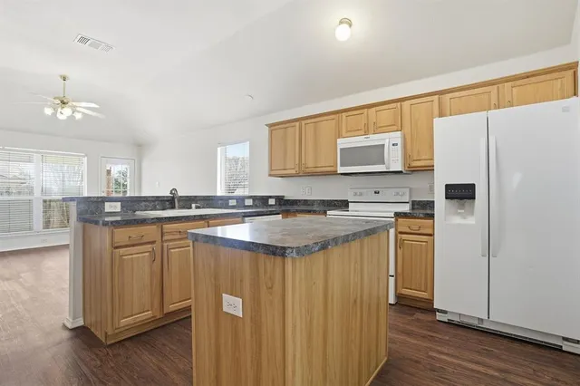 a kitchen with stainless steel appliances granite countertop a refrigerator a sink dishwasher and a stove with wooden floor