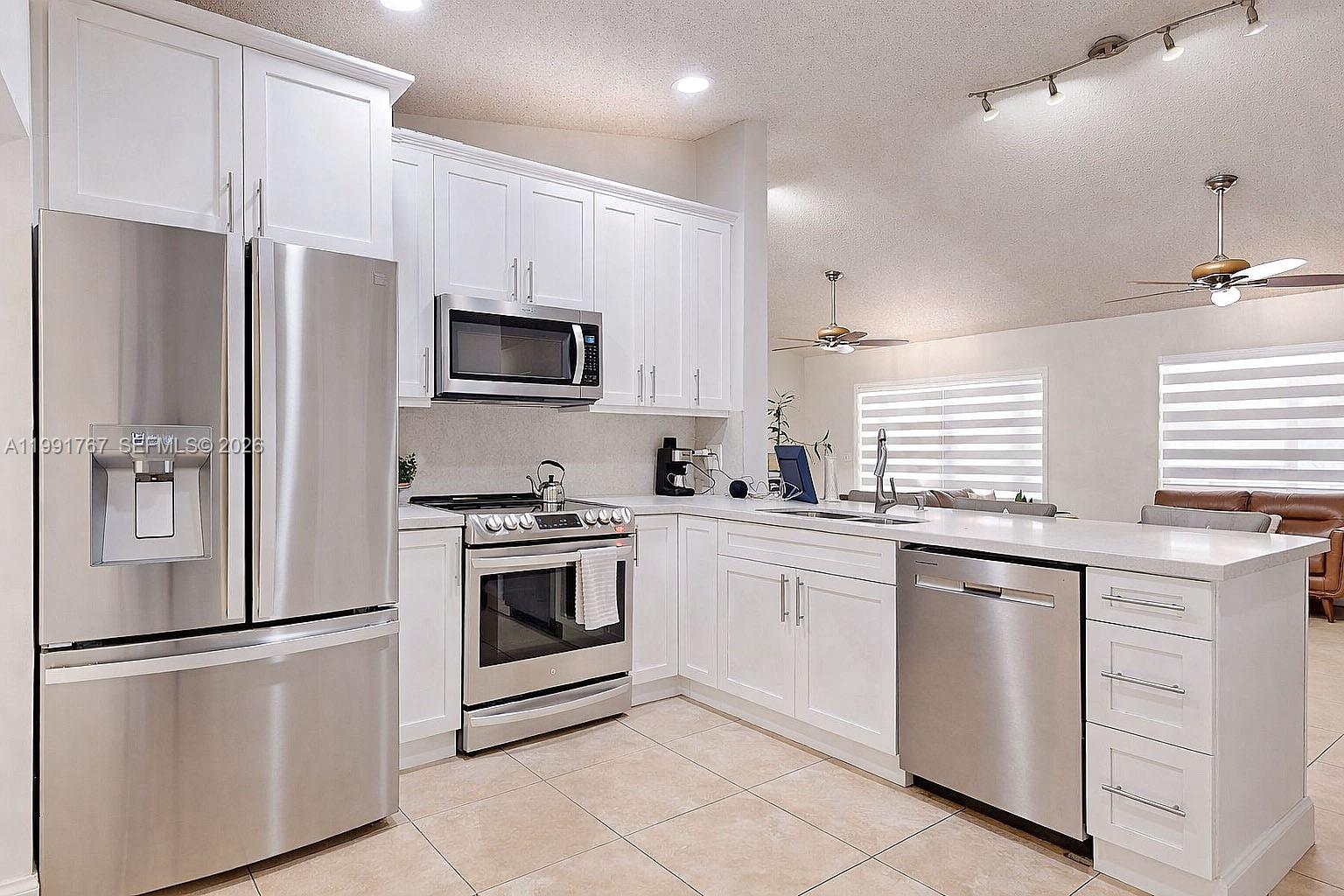 15382 Southwest 153rd Street Miami, FL 33187 - Photo 33 of 65 a kitchen with white cabinets and stainless steel appliances