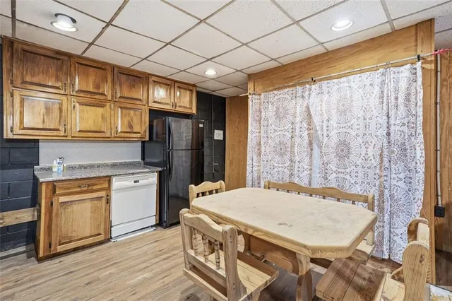 a kitchen with stainless steel appliances granite countertop a refrigerator a sink dishwasher and wooden cabinets with wooden floor