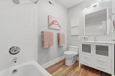 a bathroom with a toilet sink vanity tub and mirror