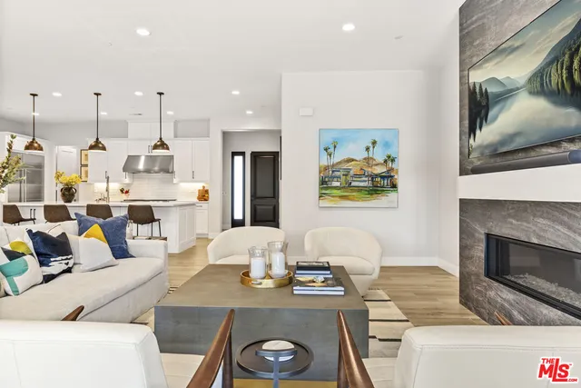 a living room with stainless steel appliances furniture a rug and a view of kitchen