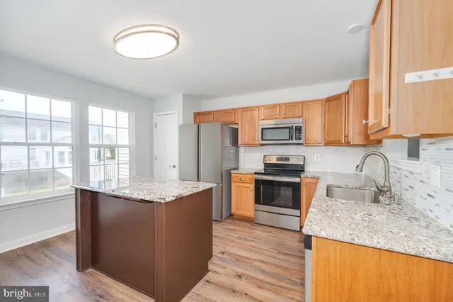 a kitchen with sink a refrigerator and wooden floor