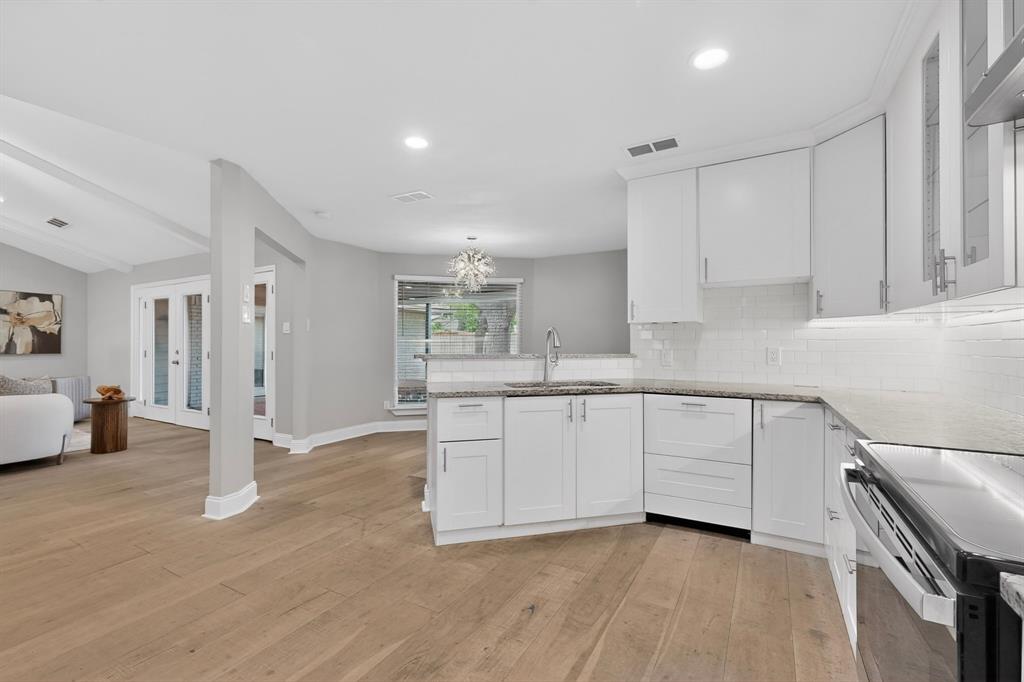 7631 Meadow Road Dallas, TX 75230 - Photo 14 of 40 A bright kitchen featuring white cabinets and warm hardwood floors