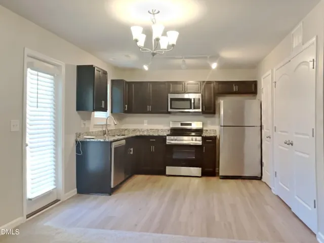 a kitchen with kitchen island granite countertop stainless steel appliances refrigerator stove microwave and cabinets