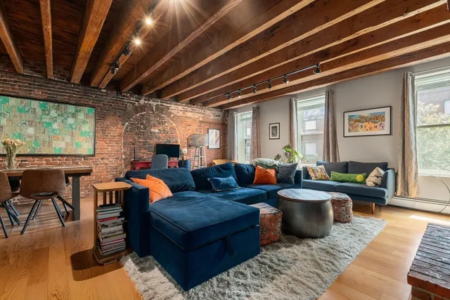 a living room with furniture a fireplace wooden floor and a window