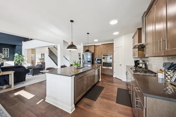 a kitchen with stainless steel appliances granite countertop a sink a stove and a wooden floors