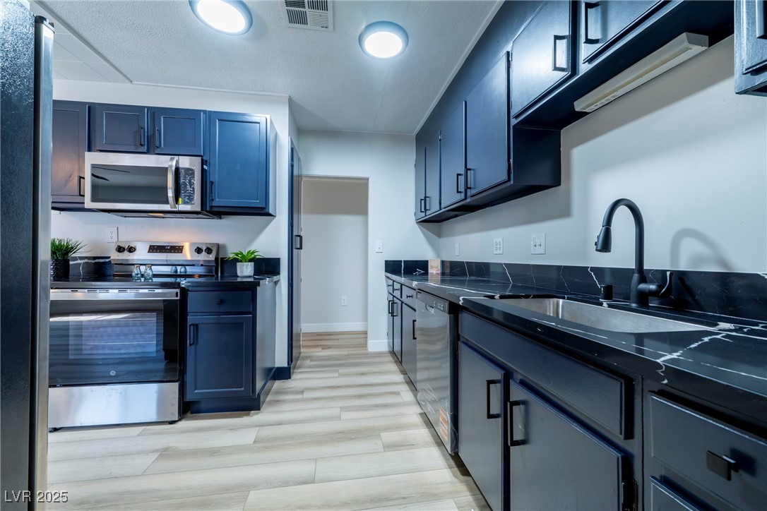 238 Kansas Avenue Henderson, NV 89015 - Photo 13 of 61 Kitchen with stainless steel appliances, light wood-style floors, and dark stone counters