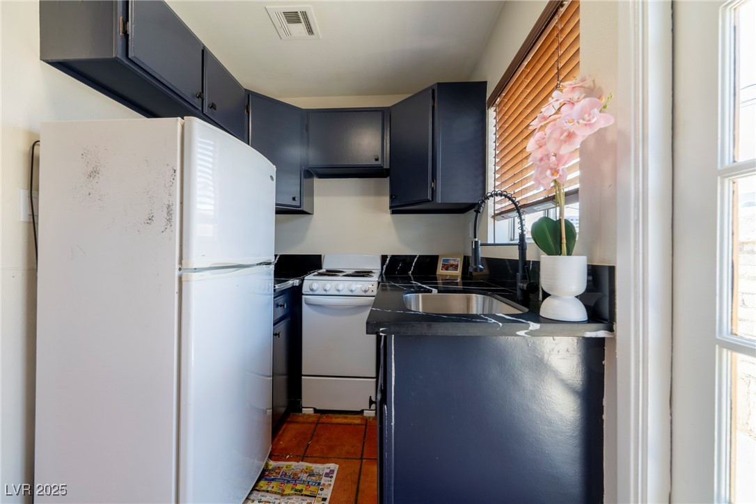238 Kansas Avenue Henderson, NV 89015 - Photo 50 of 61 Kitchen featuring dark countertops, white appliances, healthy amount of natural light, and dark tile patterned floors