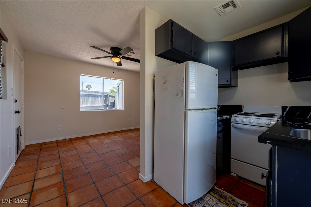 238 Kansas Avenue Henderson, NV 89015 - Photo 51 of 61 Kitchen featuring white appliances, ceiling fan, a textured ceiling, light tile patterned floors, and dark countertops