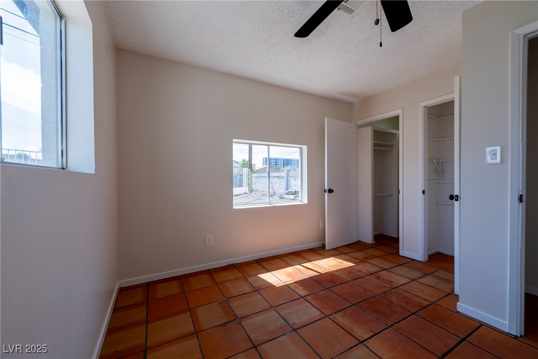 238 Kansas Avenue Henderson, NV 89015 - Photo 56 of 61 Unfurnished bedroom featuring tile patterned floors, ceiling fan, a textured ceiling, and two closets